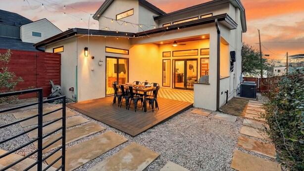 Ein modernes Haus mit einer überdachten Terrasse, einem Essbereich und einer Garage.