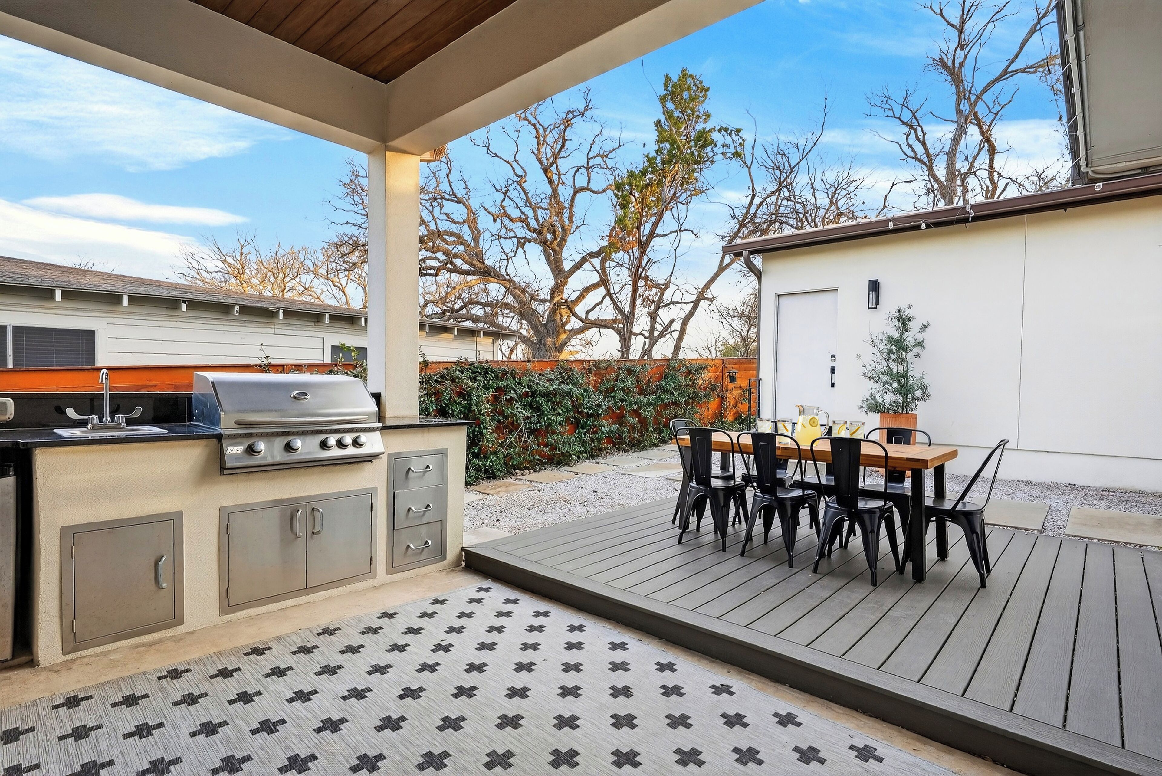Une terrasse extérieure équipée d’un barbecue, d’une table à manger et de chaises.