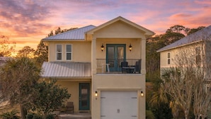 Une maison à deux étages avec un garage, un balcon et un jardin bien entretenu.