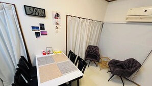 Une pièce de taille modeste comprenant une table à manger, deux chaises, un petit canapé et un climatiseur fixé au mur.