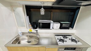 Une cuisine de taille réduite, équipée d’un évier, d’une cuisinière et d’un four à micro-ondes.