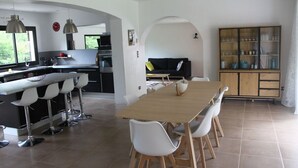Una cucina moderna con zona pranzo, sedie bianche e un tavolo di legno.