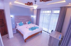 A modern bedroom with a wooden bed, a chandelier, and a large window with curtains. - Lantana Hotel Kitui (Kitui)