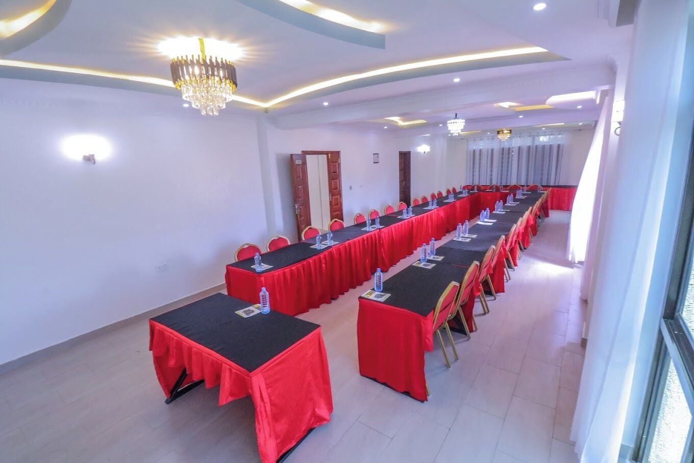 Un salón de conferencias con mesas largas, manteles rojos y sillas doradas.