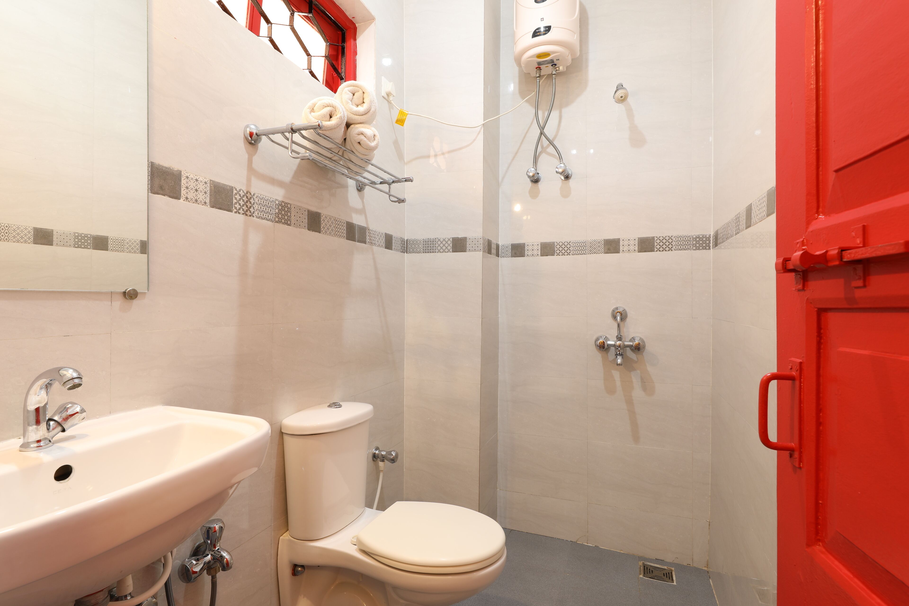 A bathroom with a sink, toilet, shower, and a red door.