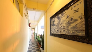 A hallway with a checkered floor, potted plants, and a framed artwork on the wall. - TELES WESTEND HOTEL (Vasco da Gama)