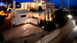 Un bâtiment moderne à deux étages, doté d’un balcon, entouré d’arbres et offrant une vue sur la mer.