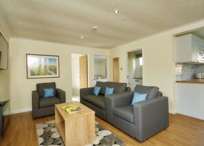 Ein Wohnzimmer mit zwei grauen Sofas, einem Holztisch und einem Teppich.