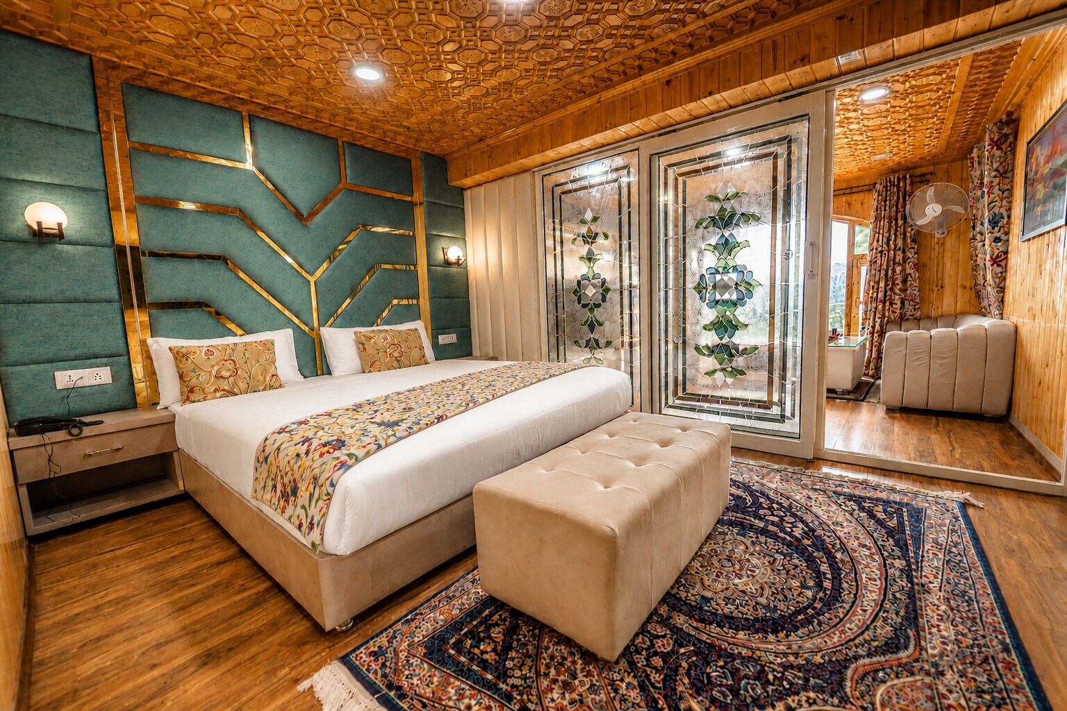 A bedroom with a large bed, a bench, a patterned rug, and a wooden ceiling.