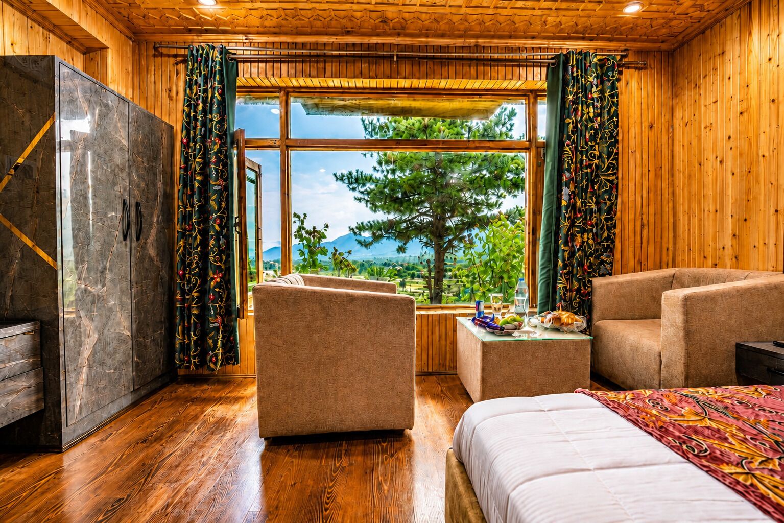 A room with a bed, two sofas, a small table, and a large window with curtains.