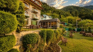 A multi-story hotel with outdoor seating and a view of a mountainous landscape. - SRICHAN RESORTS (Pahalgam)