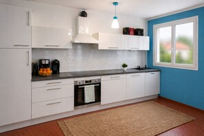 Eine moderne Küche mit weißen Schränken, einem eingebauten Backofen, einer Kaffeemaschine und einem Fenster mit Blick.