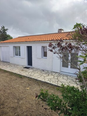 A single-story house with a tiled roof, white exterior walls, and a stone-paved entrance. - 3-Bedroom House "Jard sur Mer" (Jard-sur-Mer)