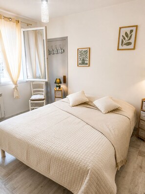 Ein Schlafzimmer mit einem großen Bett, einem Nachttisch mit Lampe, einem Sessel, einem Kleiderschrank und einem Spiegel.
