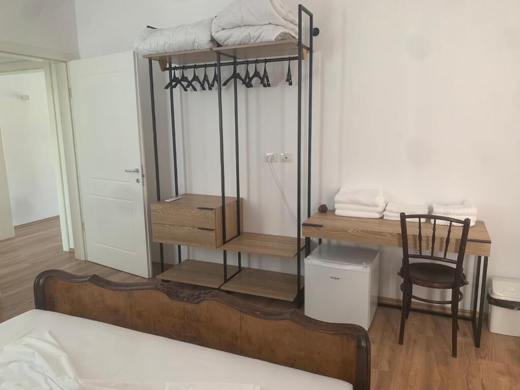 Un dormitorio con una cama litera, un escritorio con silla, un refrigerador pequeño y una mesita de noche.