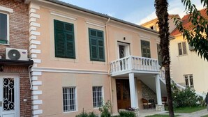A two-story building with a balcony, a stone staircase, and a small garden area. - Vintage  (Shkoder)