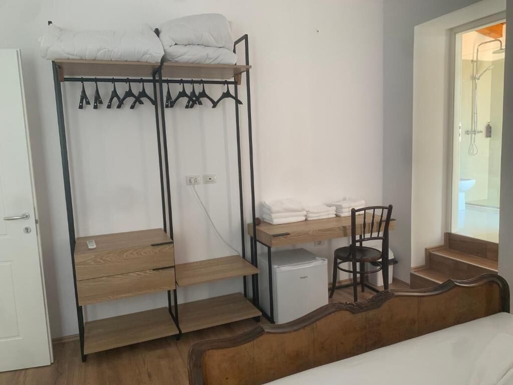 Une chambre de dortoir avec des lits superposés, un bureau avec une chaise, un petit réfrigérateur et une douche visible à travers une porte ouverte.
