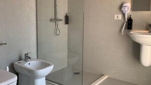 A modern bathroom with a glass-enclosed shower, a bidet, and a sink. - Vintage  (Shkoder)