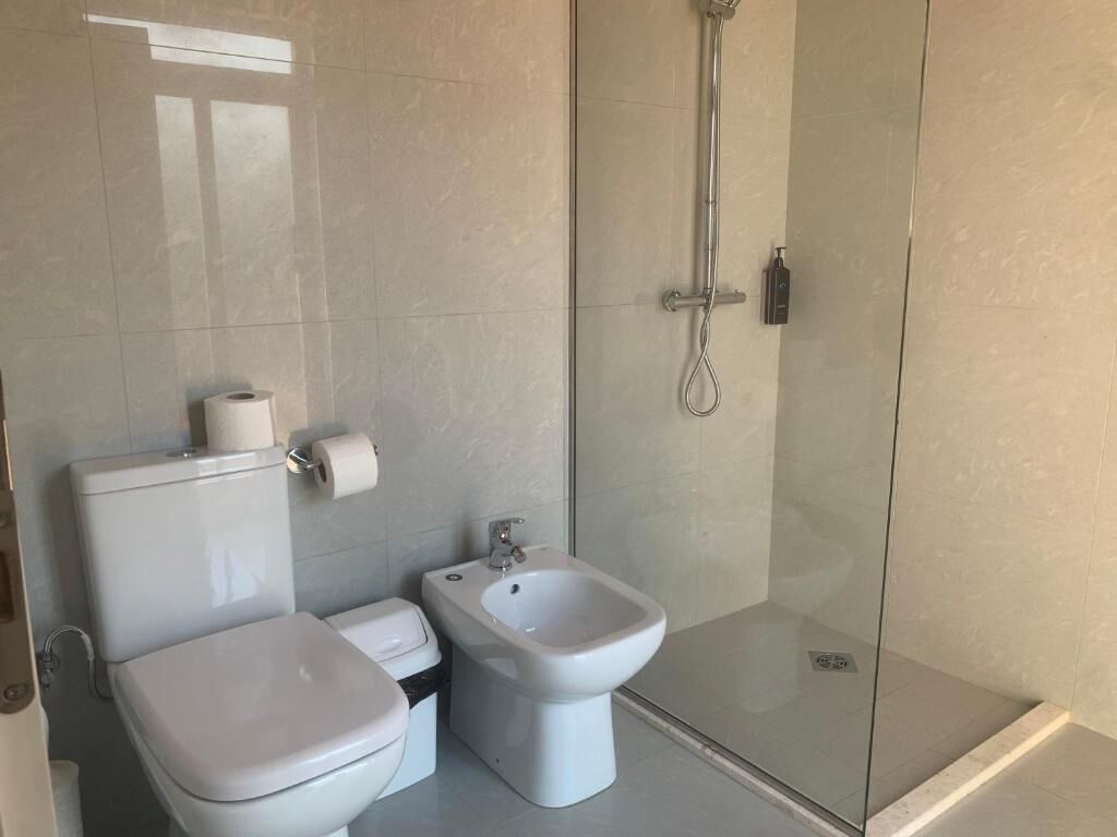 A modern bathroom with a toilet, bidet, and glass-enclosed shower.