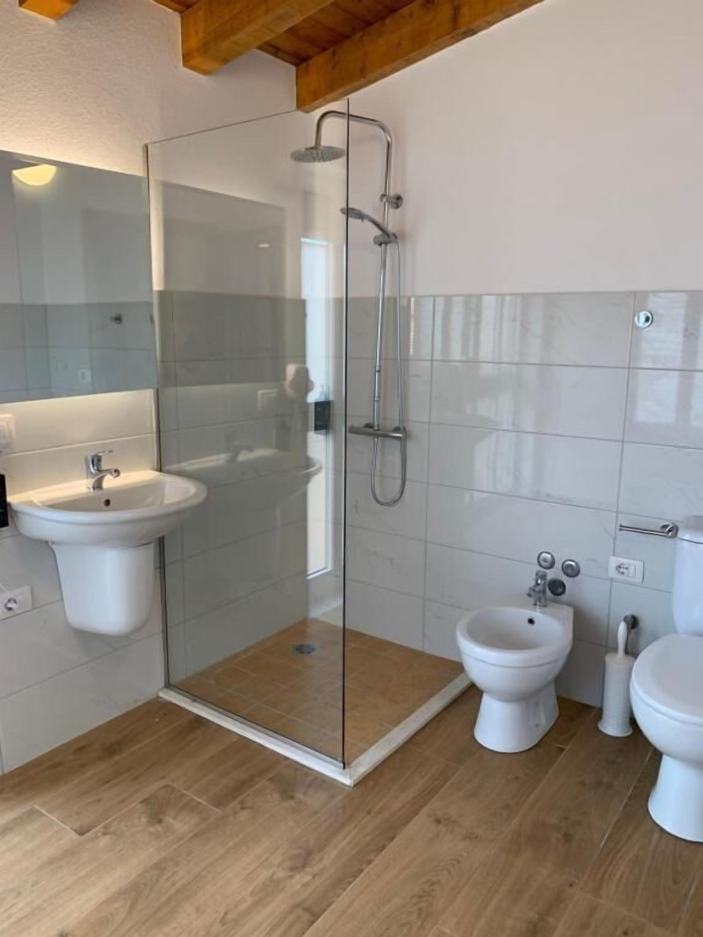 Un baño moderno con ducha de vidrio, lavabo pedestal, bidé y retrete.