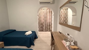 A hotel room with two single beds, a wooden desk with a telephone and a kettle, and an air conditioning unit on the wall. - Accommodation Corallo (Rome)