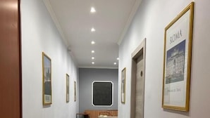 A hallway with a desk, a bed, and a framed picture of Rome on the wall. - Accommodation Corallo (Rome)