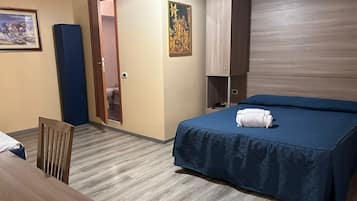 A hotel room with a bed, a desk, a chair, a wardrobe, and a door leading to a bathroom.