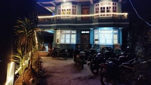 Een meerlaags gebouw met een balkon, een parkeerplaats voor motorfietsen en een bord waarop een restaurant wordt aangegeven.
