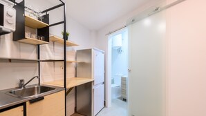 Cuina compacta amb un rentapeus, un frigorífic de portes dobles i una petita barra.