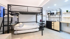 Un llit superposat amb escriptori i petita cuina integrada en una habitació moderna.