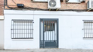 La façana d'un edifici amb exterior blanc, una porta metàl·lica i finestres amb reixes.