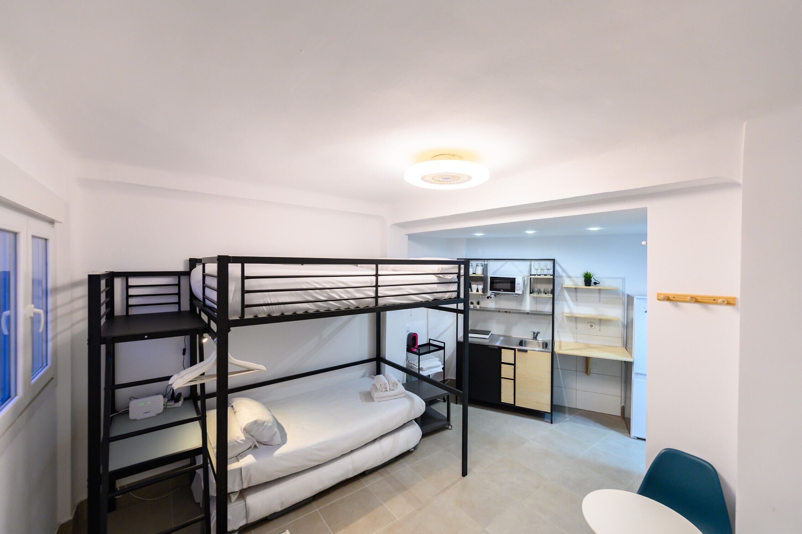 A bunk bed room with a kitchenette and a desk.