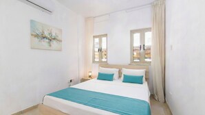 A bedroom with a bed, a window, a painting, and a nightstand. - 4 bedroom villa by Fig tree bay beach (Protaras)