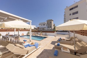 A rooftop pool area with lounge chairs, umbrellas, and a small table with a drink. - 4 bedroom villa by Fig tree bay beach (Protaras)