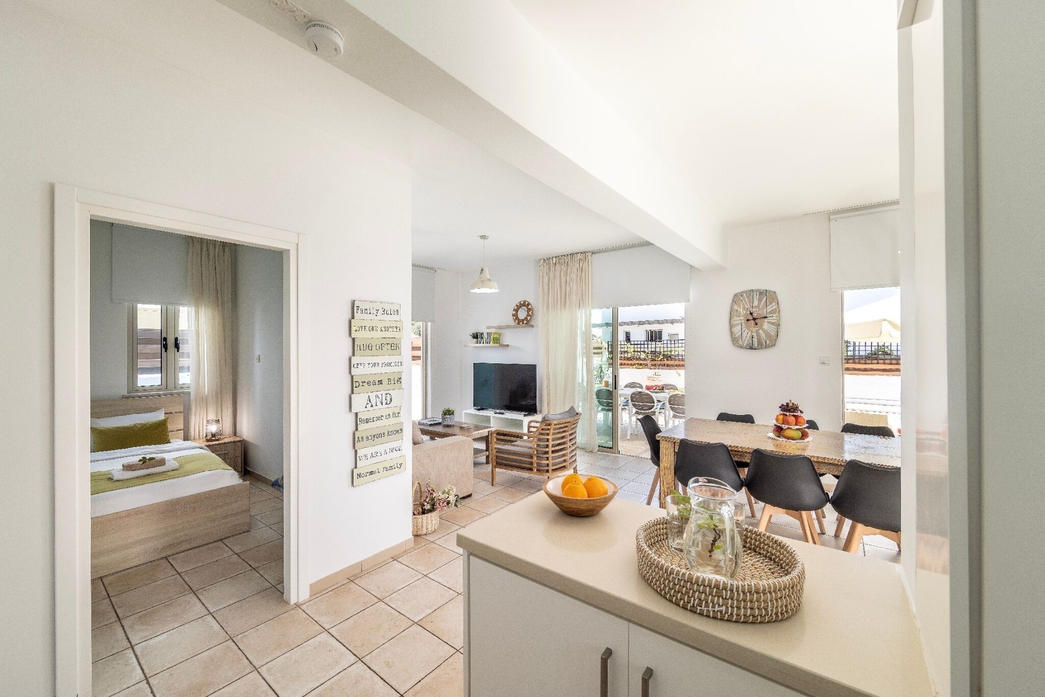 A modern living space with a kitchen, dining area, and a bedroom with a large bed and a TV.