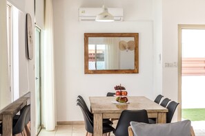 A dining area with a wooden table, black chairs, a mirror, and a fruit centerpiece. - 4 bedroom villa by Fig tree bay beach (Protaras)