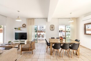 A spacious living area with a TV, seating, and a dining table. - 4 bedroom villa by Fig tree bay beach (Protaras)