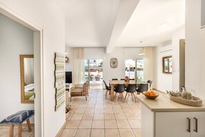 A spacious kitchen with a dining area, a view to the outside, and a living room with a sofa and a TV. - 4 bedroom villa by Fig tree bay beach (Protaras)