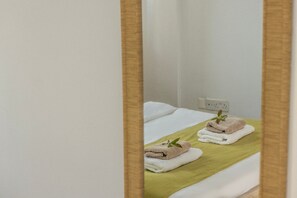 A hotel room with a bed, a green towel, and a white pillow. - 4 bedroom villa by Fig tree bay beach (Protaras)