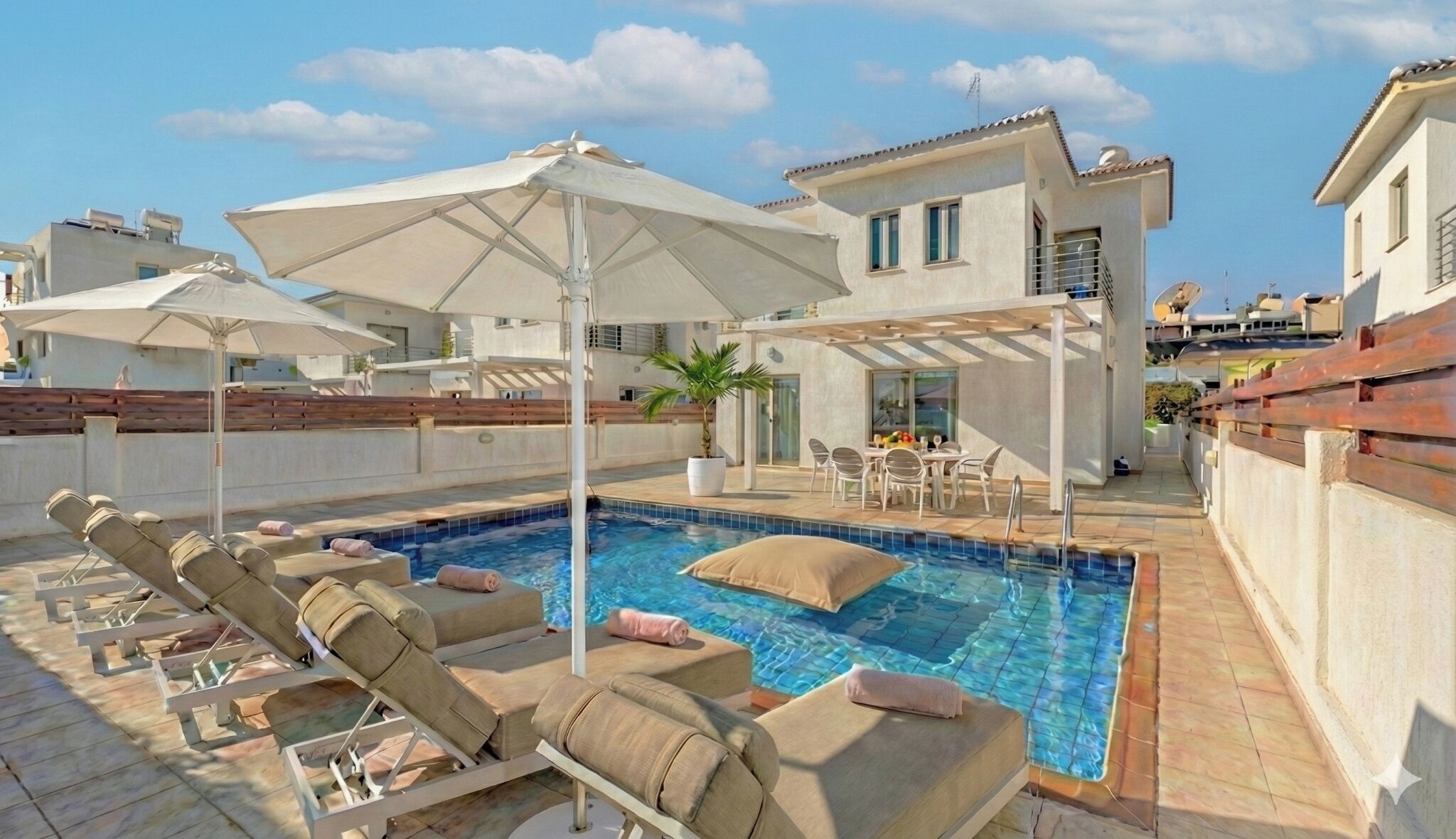 A rooftop pool area with lounge chairs, umbrellas, and a dining setup.