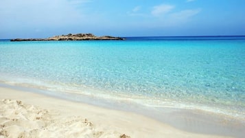 En strand med kristallklart turkost vatten och en sandstrand.