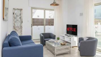 Ett modernt vardagsrum med en soffa, fåtöljer, ett soffbord och en tv som visar Netflix.