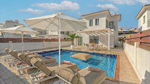 A rooftop pool area with lounge chairs, umbrellas, and a dining setup. - 4 bedroom villa by Fig tree bay beach (Protaras)