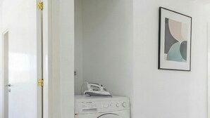 A compact laundry room with a front-loading washing machine and an iron. - 4 bedroom villa by Fig tree bay beach (Protaras)