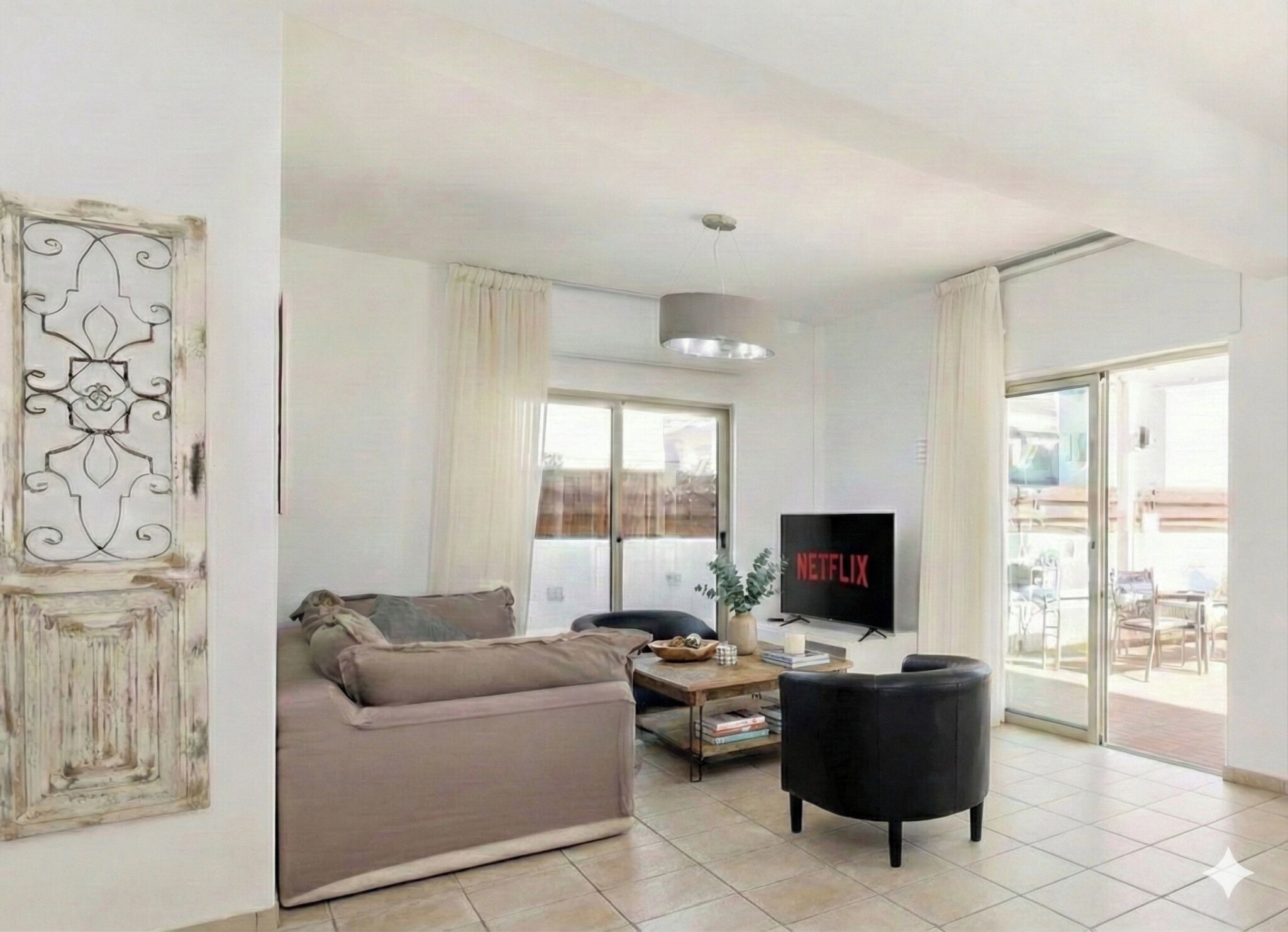 A living room with a sofa, a black armchair, a coffee table, and a TV displaying 'NETFLIX'.