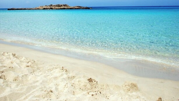 Una spiaggia con acque cristalline turchesi e una riva sabbiosa.