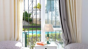 A hotel room with a bed, a nightstand, a lamp, and a view of a pool. - Valparaiso by Interhome (Nerja)