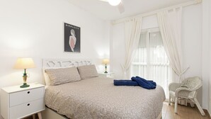 A neatly arranged bedroom with a bed, two bedside tables with lamps, a chair, and a window with curtains. - Valparaiso by Interhome (Nerja)