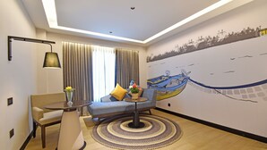 A modern living room with a sofa, a round table, a lamp, and a decorative rug. - Hotel Sands Point (Puducherry)