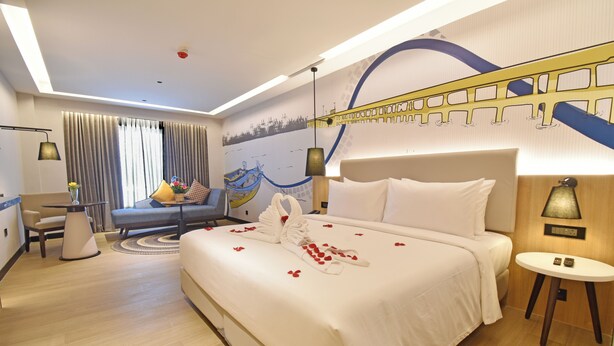 A modern hotel room with a large bed, a desk, and a sofa. - Hotel Sands Point (Puducherry)